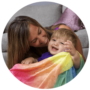Mom and toddler sitting on the floor and playing with a movement scarf