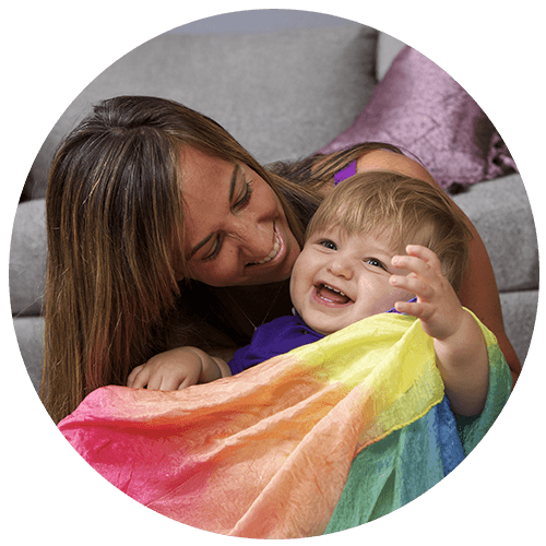 Mom and toddler sitting on the floor and playing with a movement scarf