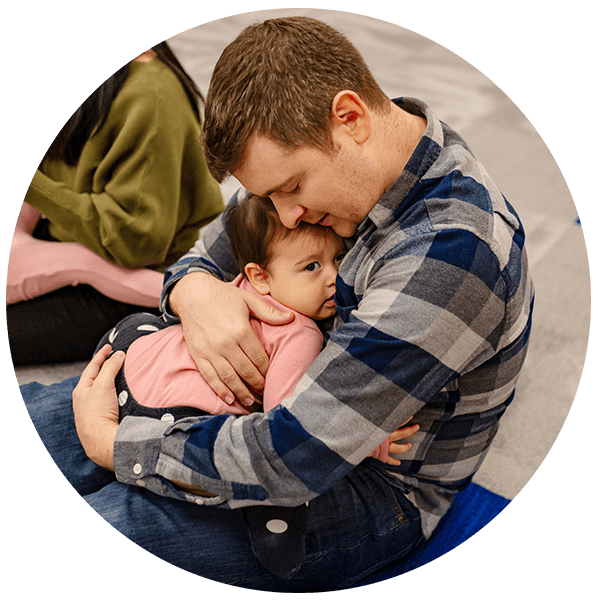 Dad with eyes closed holding daughter close in lap