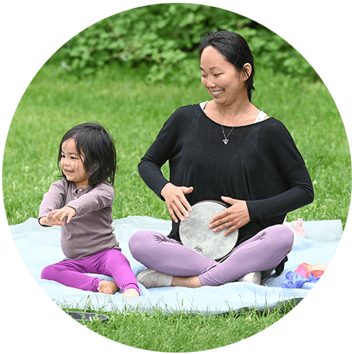 mom and child sitting on blanket outside making music together