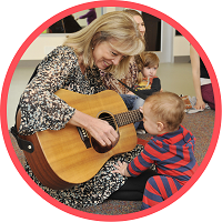 Susan Darrow playing guitar with baby